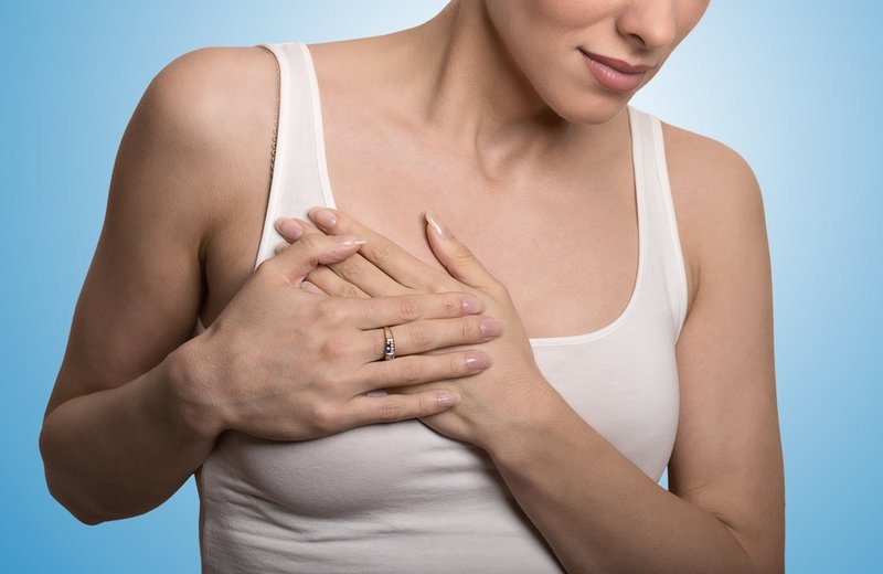 Closeup-cropped-portrait-young-woman-with-breast-pain-touching-chest-colored-isolated-on-blue-background.jpeg